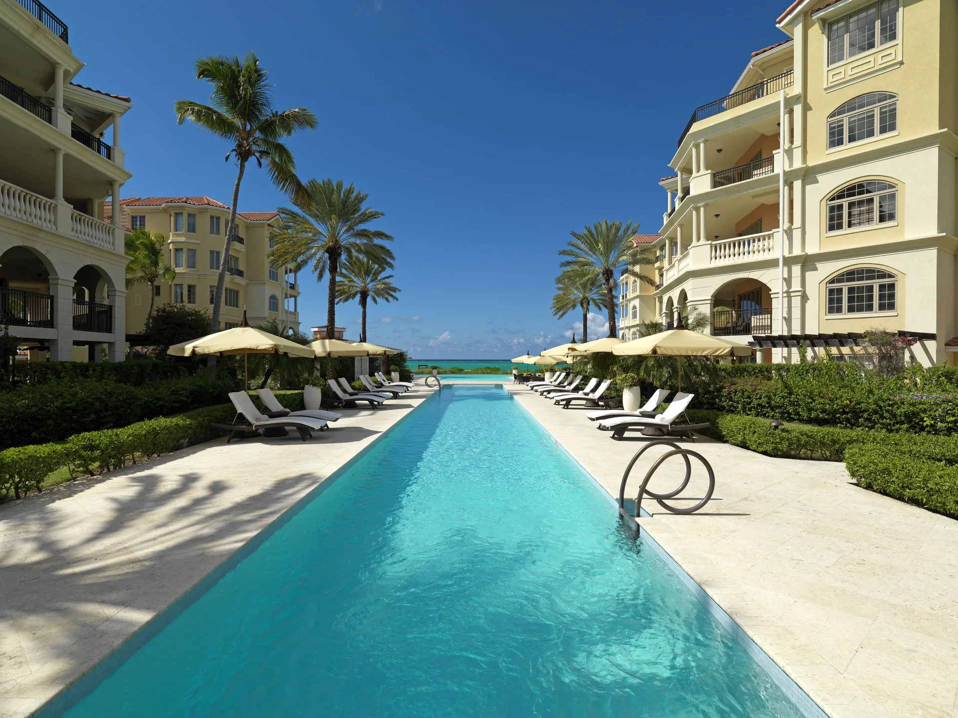 Long swimming pool with loungers between resort buildings at The Somerset on Grace Bay.