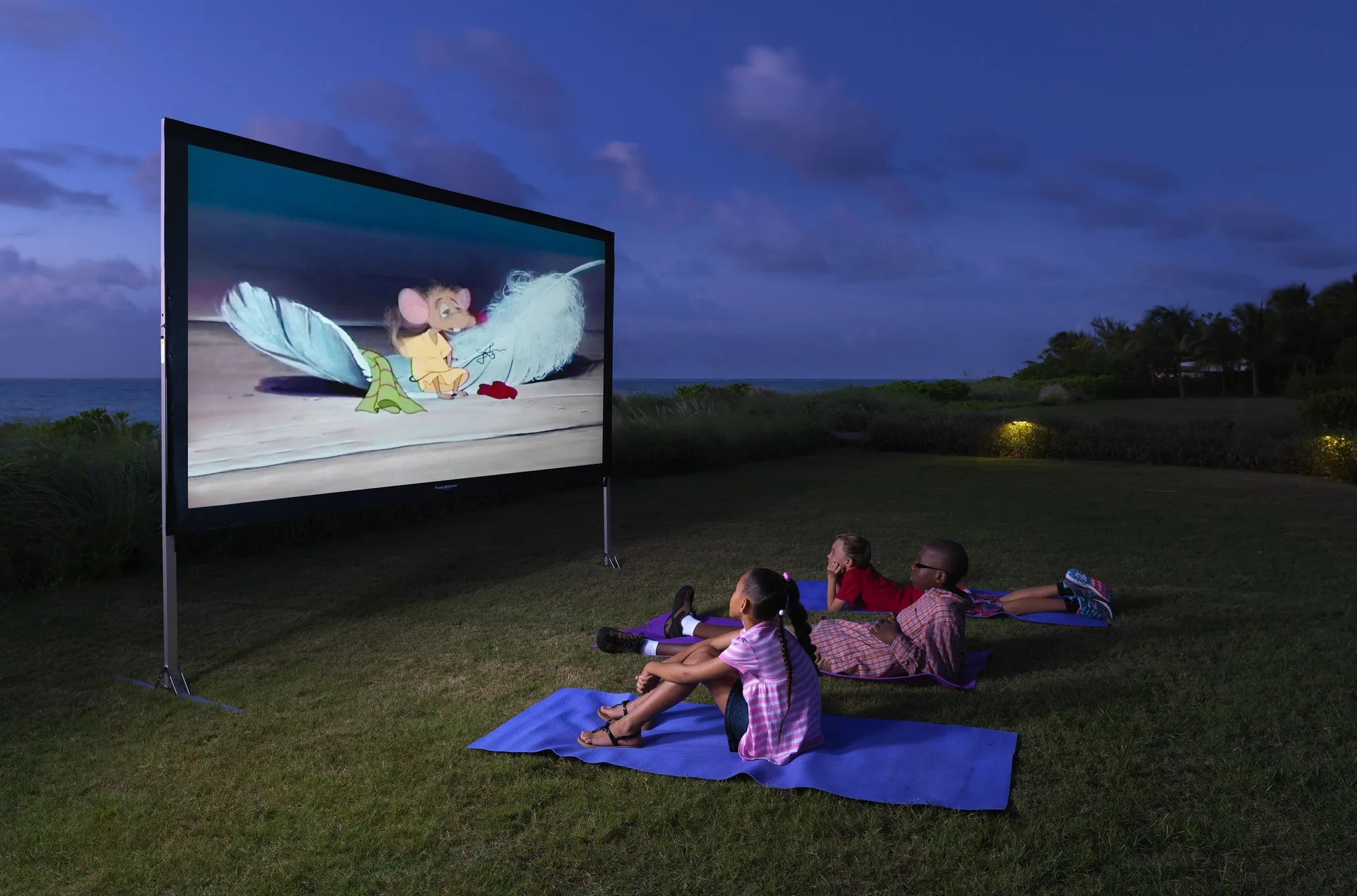 Children watching an outdoor movie on the lawn at The Somerset on Grace Bay.