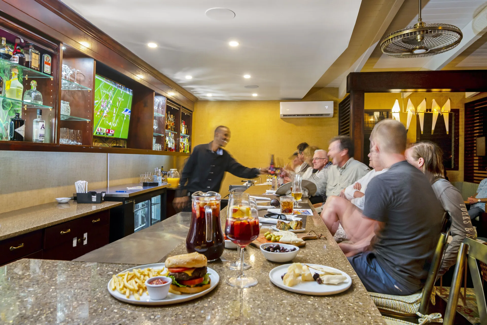 Guests seated at an indoor bar with drinks and food at The Somerset on Grace Bay.