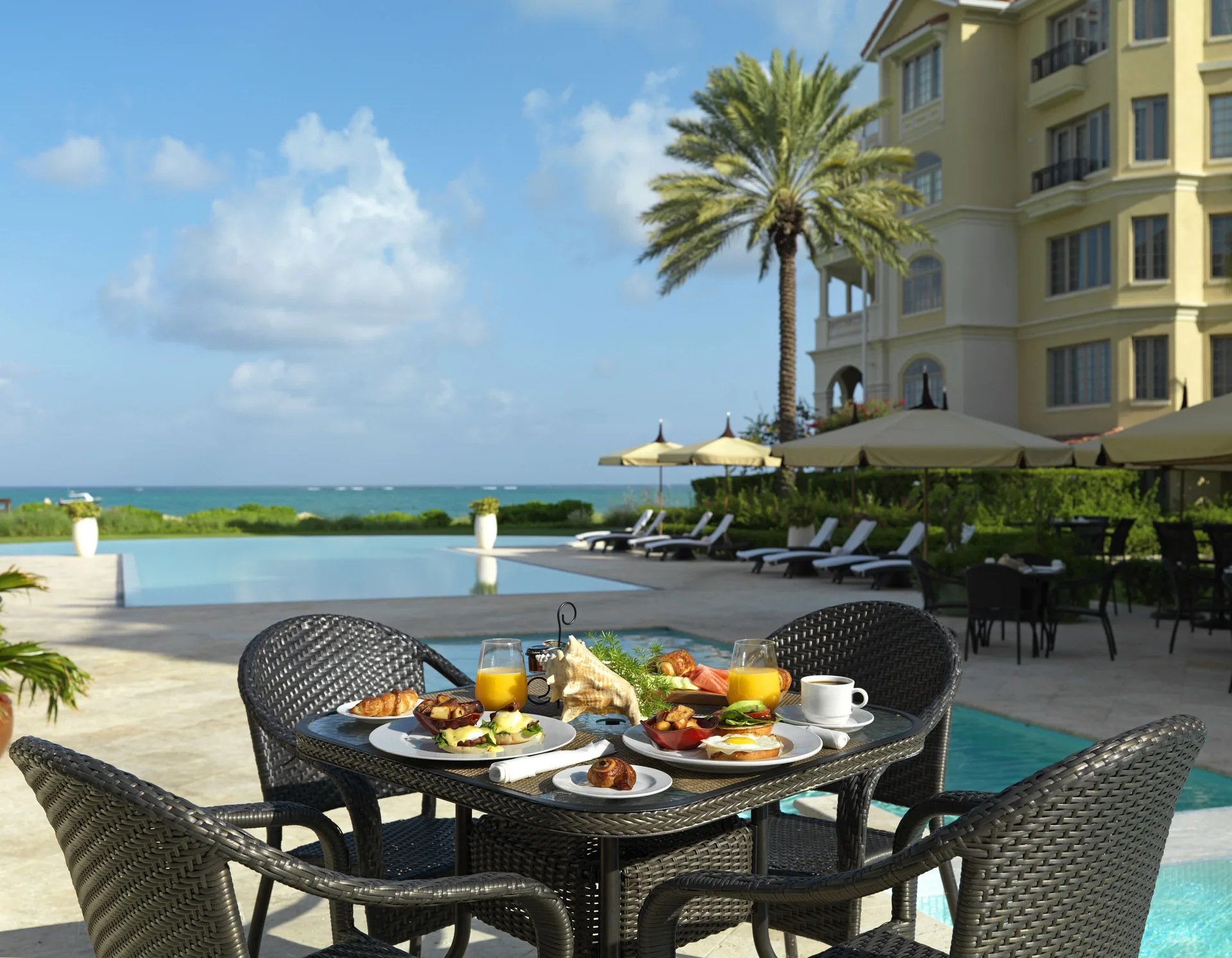 Poolside breakfast table with ocean backdrop at The Somerset on Grace Bay.