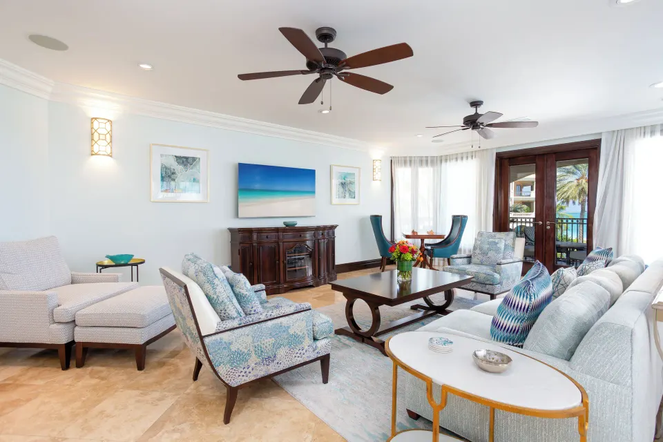 Living room with sofas, lounge chairs, and balcony doors at The Somerset on Grace Bay.