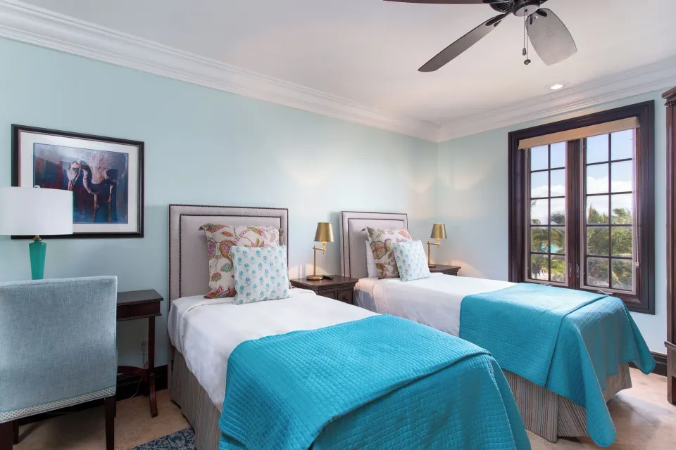 Twin beds with turquoise covers and a large window at The Somerset on Grace Bay.