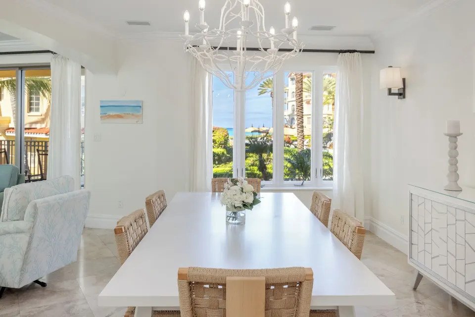 Dining area in the Family Villa at The Somerset on Grace Bay with white table, woven chairs, and large windows.
