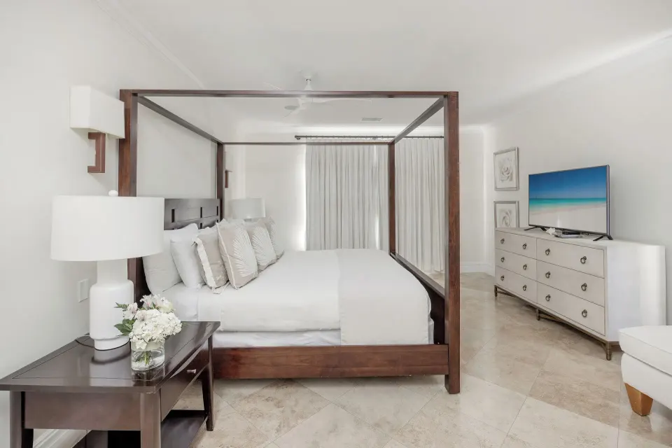 Four-poster king bedroom in the Family Villa at The Somerset on Grace Bay with dresser and television.