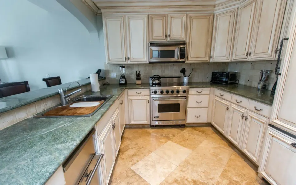 Kitchen in the Family Villa at The Somerset on Grace Bay with cream cabinetry, stone counters, and stainless range.
