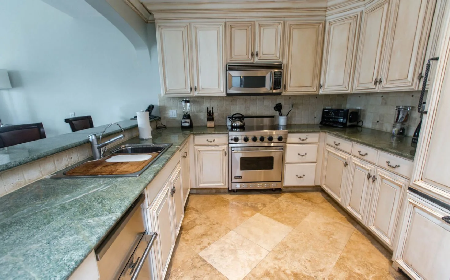 Kitchen in the Family Villa at The Somerset on Grace Bay with cream cabinetry, stone counters, and stainless range.