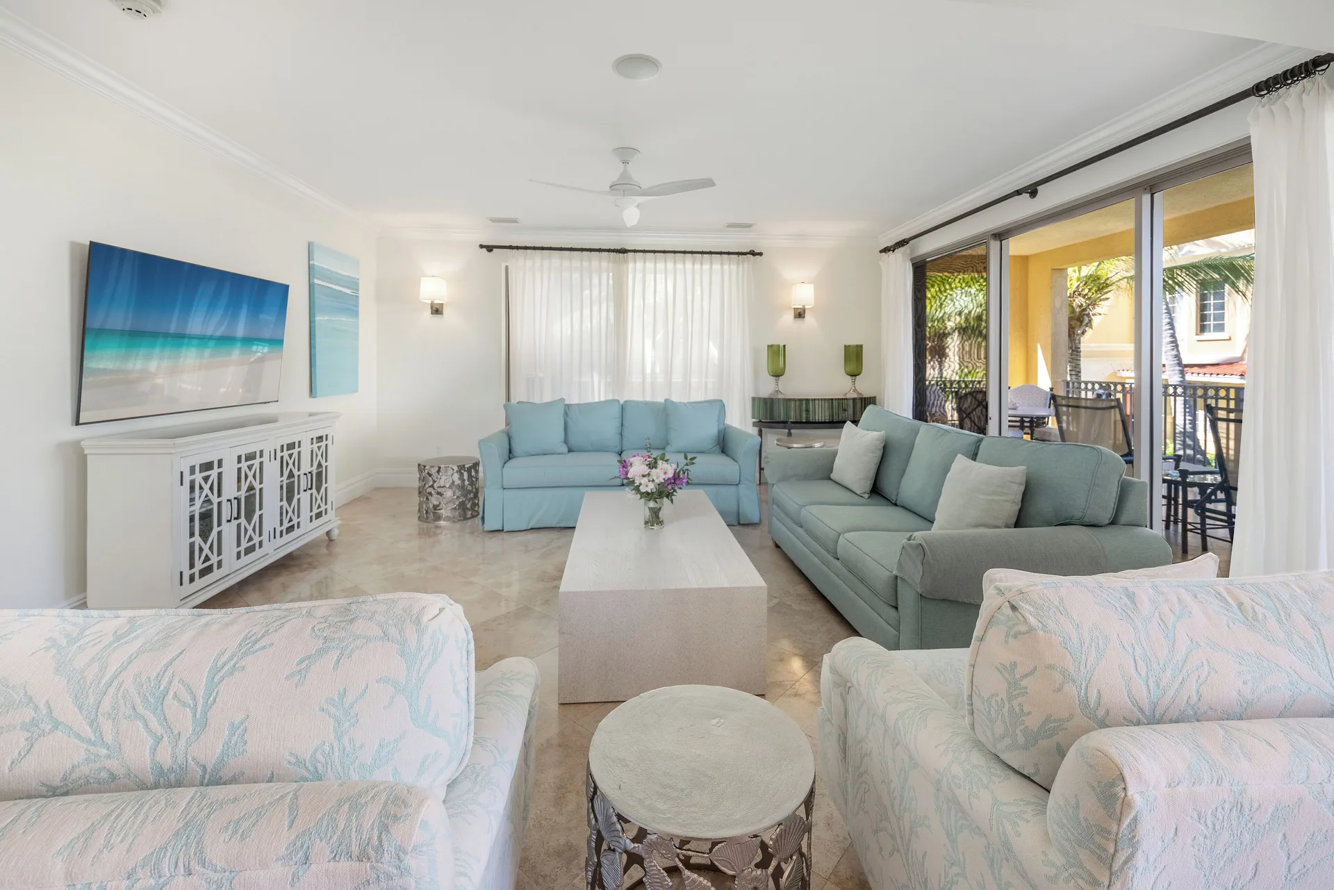 Living room in the Family Villa at The Somerset on Grace Bay with blue sofas, TV, and balcony doors.