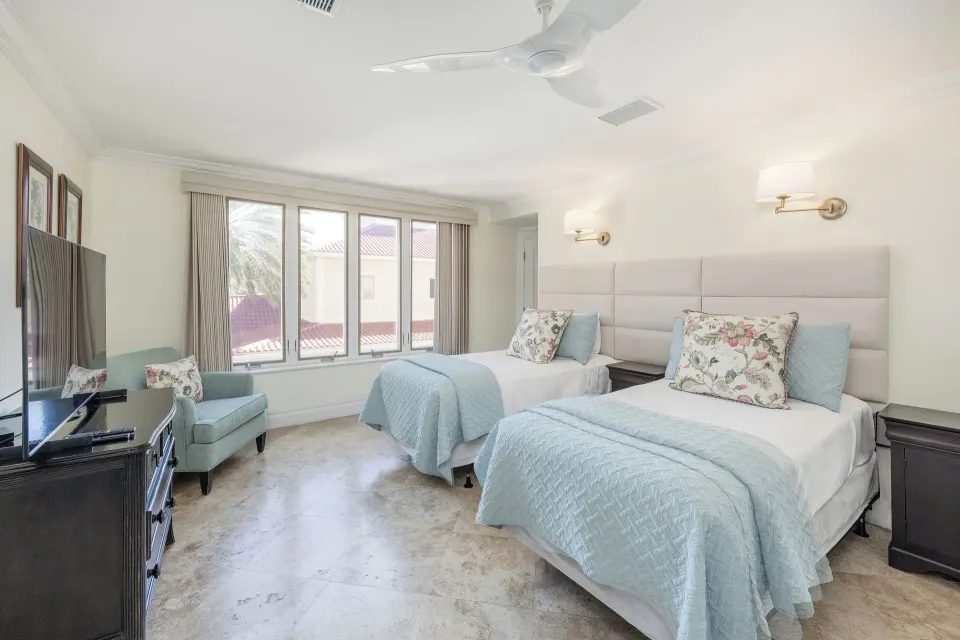 Bedroom in the Family Villa at The Somerset on Grace Bay with two beds, blue coverlets, TV, and windows.