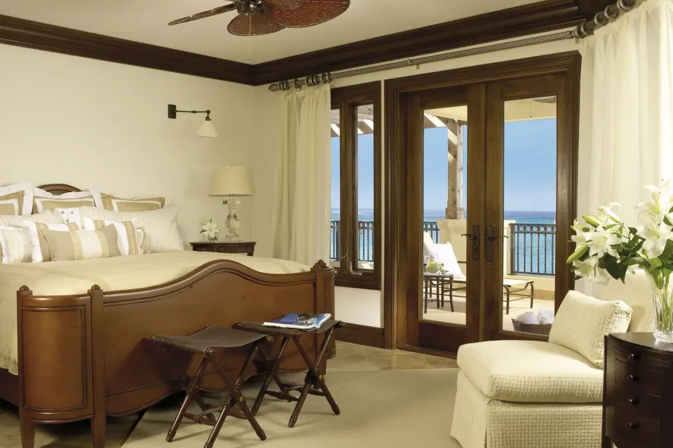 Ocean-view bedroom with wood bed and balcony doors at The Somerset on Grace Bay.