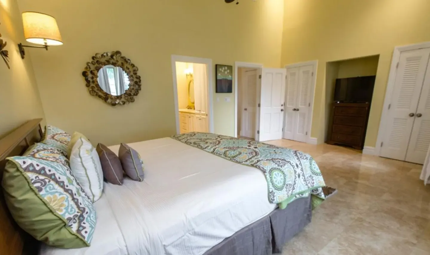 Villa ocean view bedroom with a large bed and ensuite doorway at The Somerset on Grace Bay.
