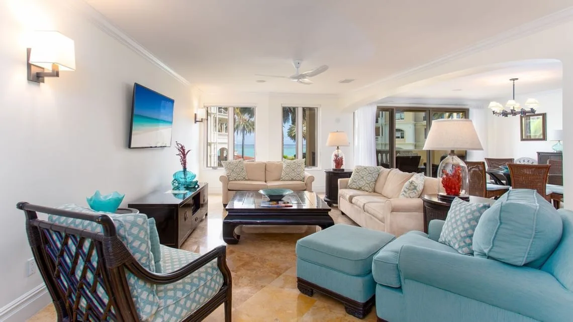 Villa ocean view living room with sofas, armchairs, and ocean-facing windows at The Somerset on Grace Bay.