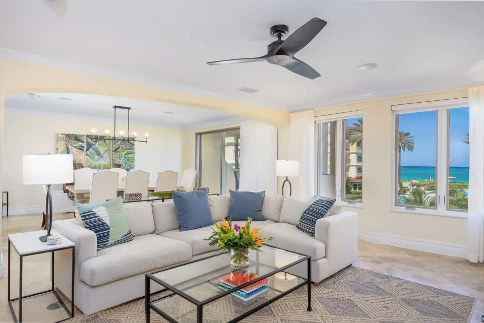 Villa ocean view living room with sofa, dining area, and sea-facing windows at The Somerset on Grace Bay.