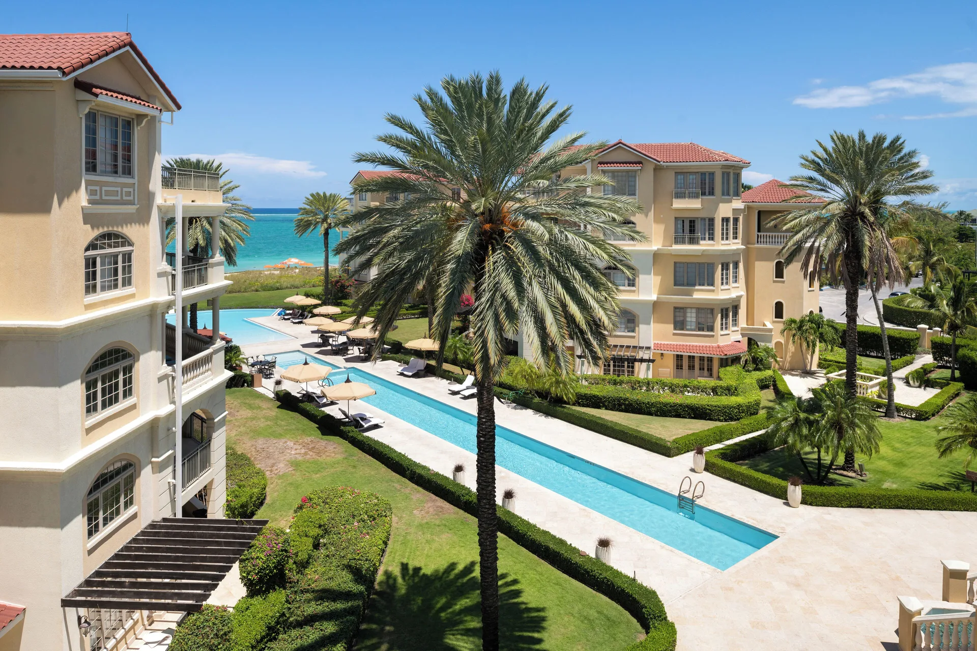 Ocean-view villa balcony view of pool, palms, and beach at The Somerset on Grace Bay.