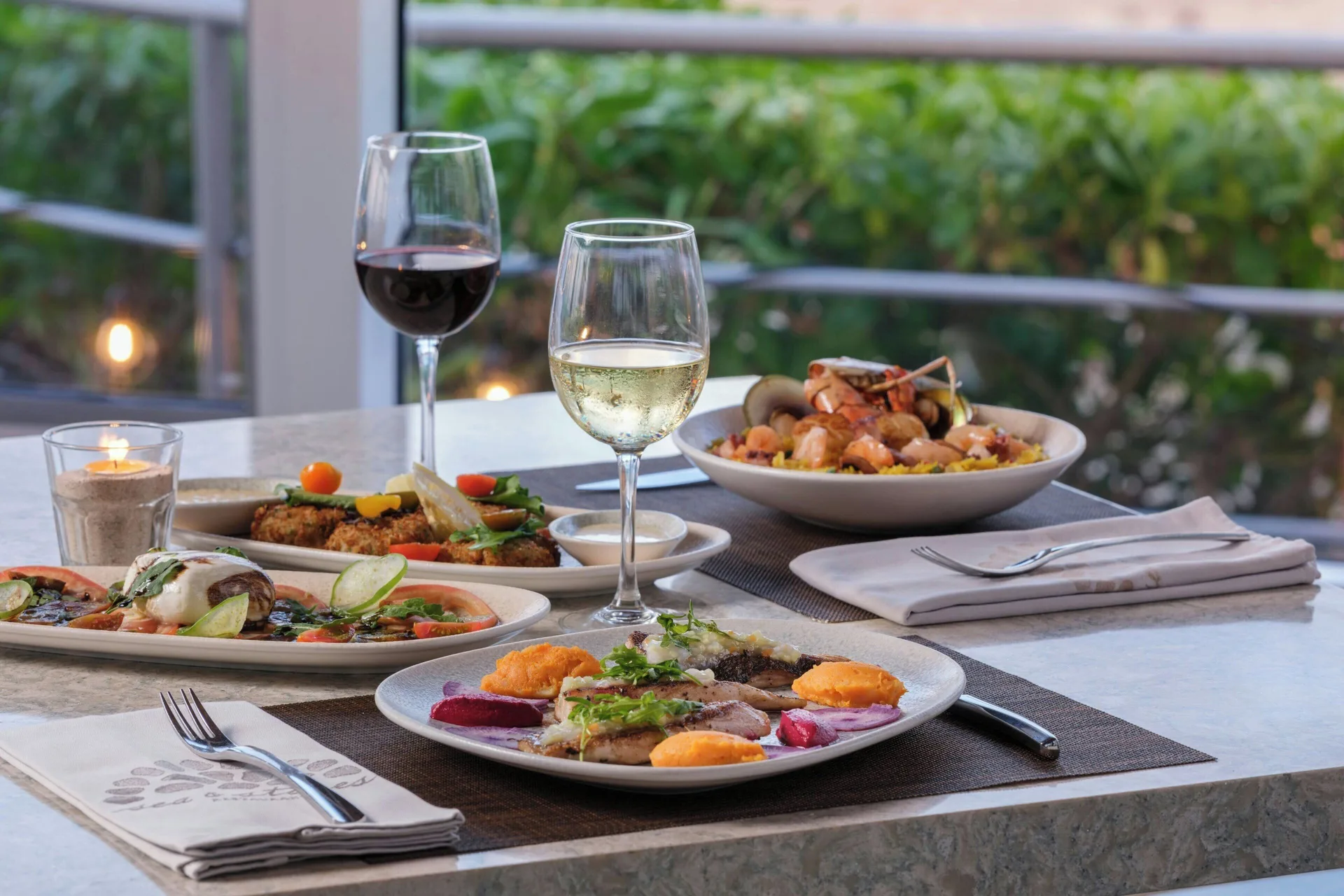 Plated seafood dishes and wine glasses on a dining table at The Westin Resort & Spa, Cancun.