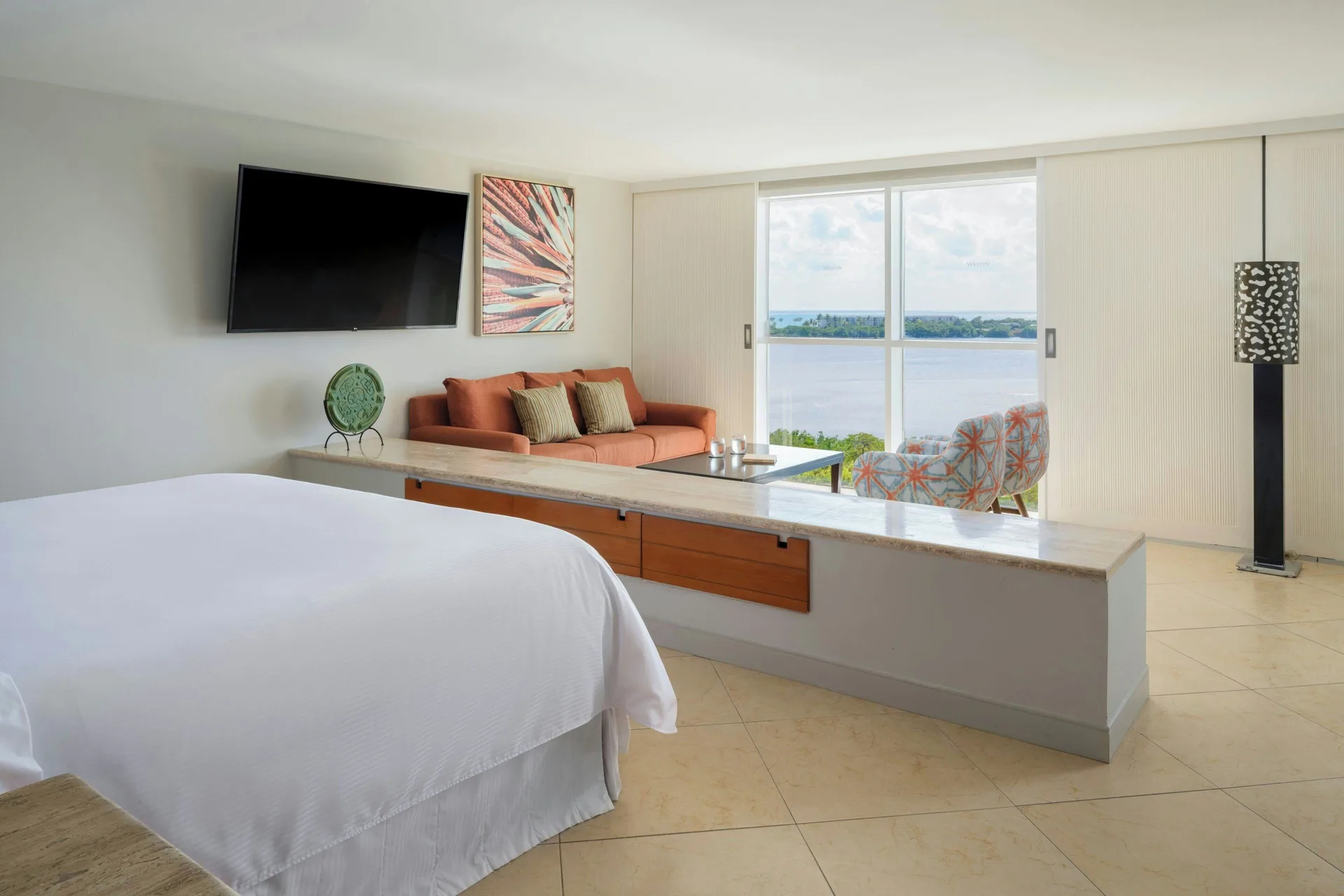 Junior Suite bedroom and sitting area with lagoon window at The Westin Resort & Spa, Cancun.