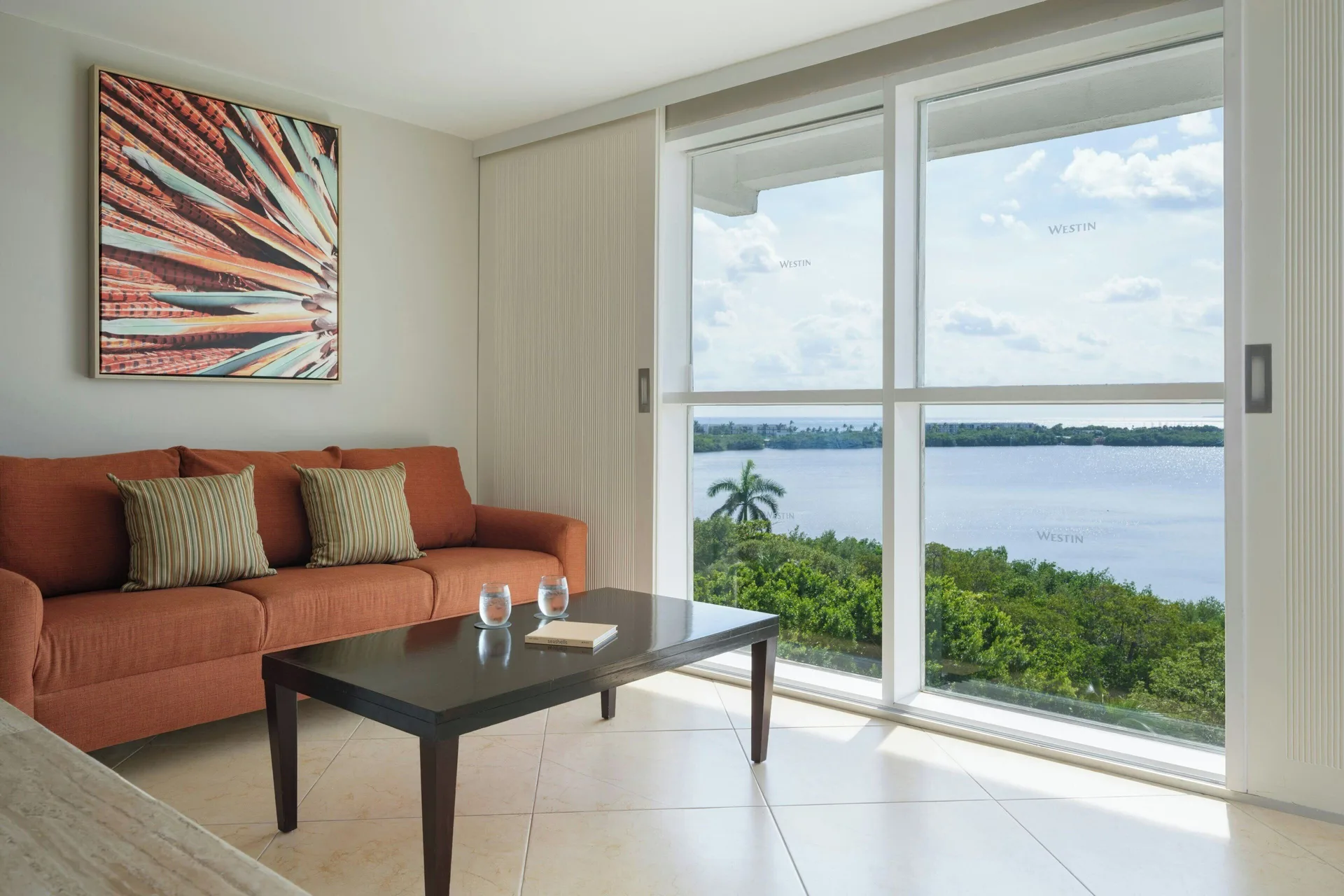 Junior Suite sitting area with orange sofa and lagoon view at The Westin Resort & Spa, Cancun.