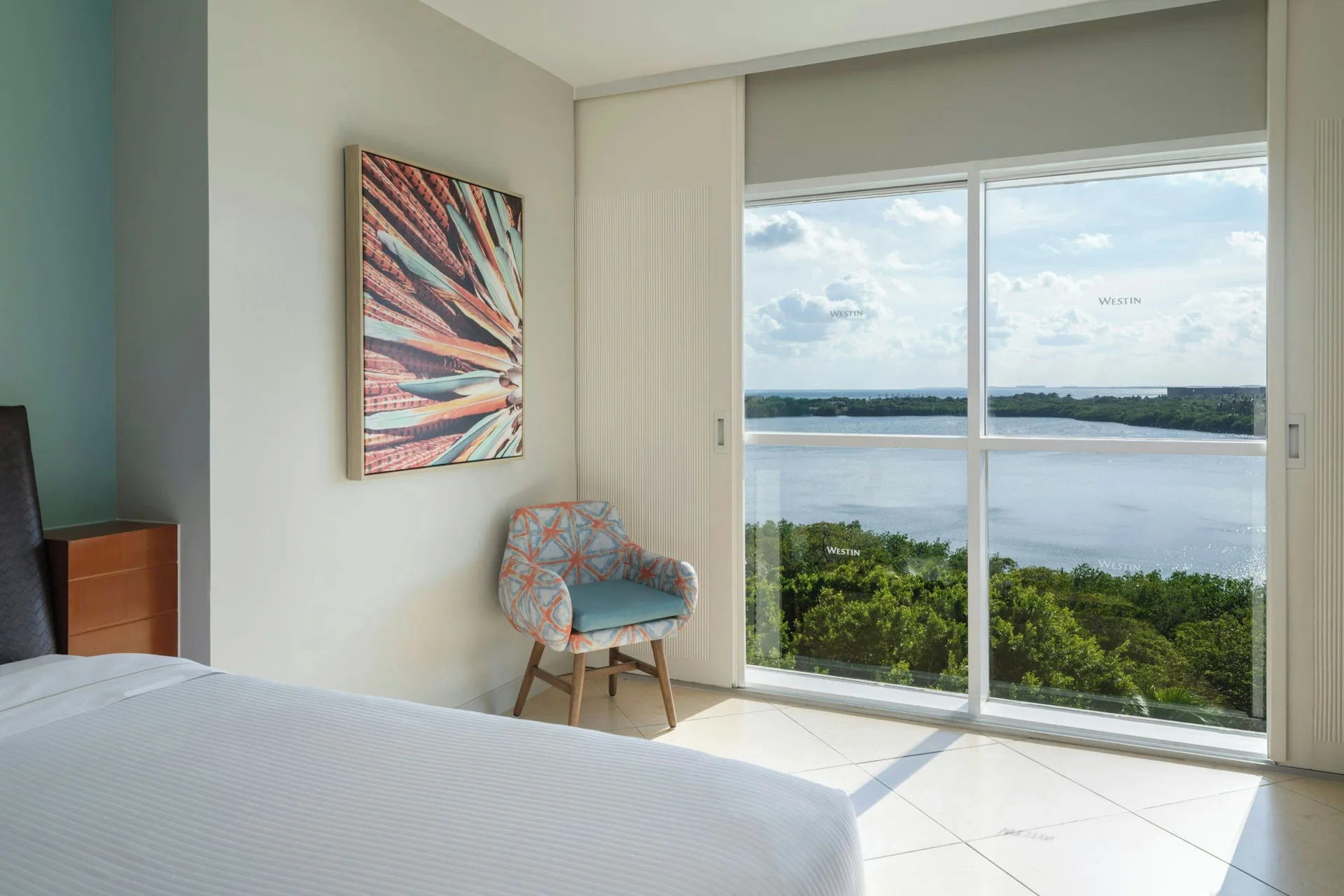 Lagoon View room window with chair and bed at The Westin Resort & Spa, Cancun.