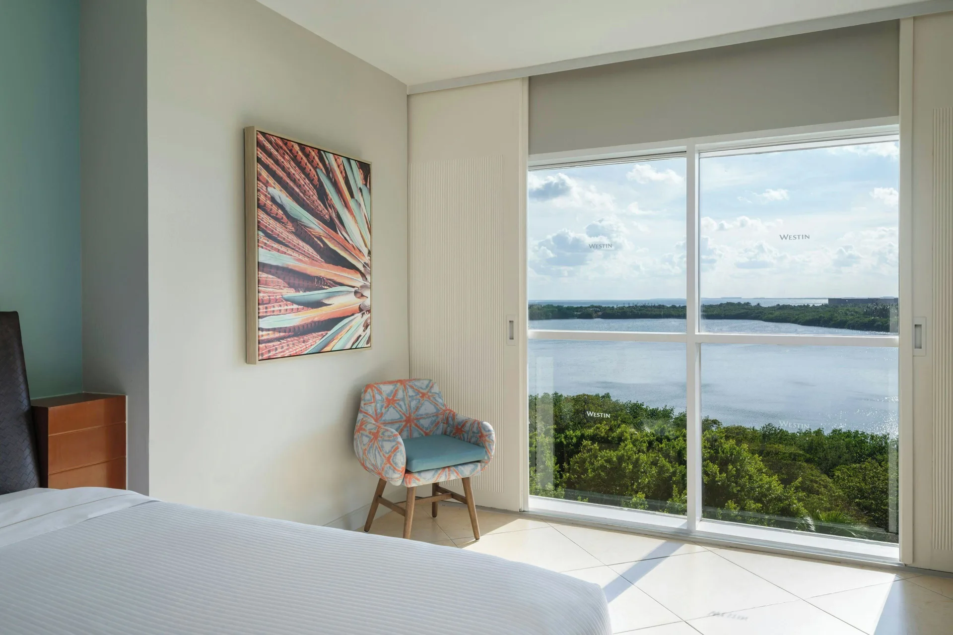 Lagoon view guest room with bed and chair at The Westin Resort & Spa, Cancun.