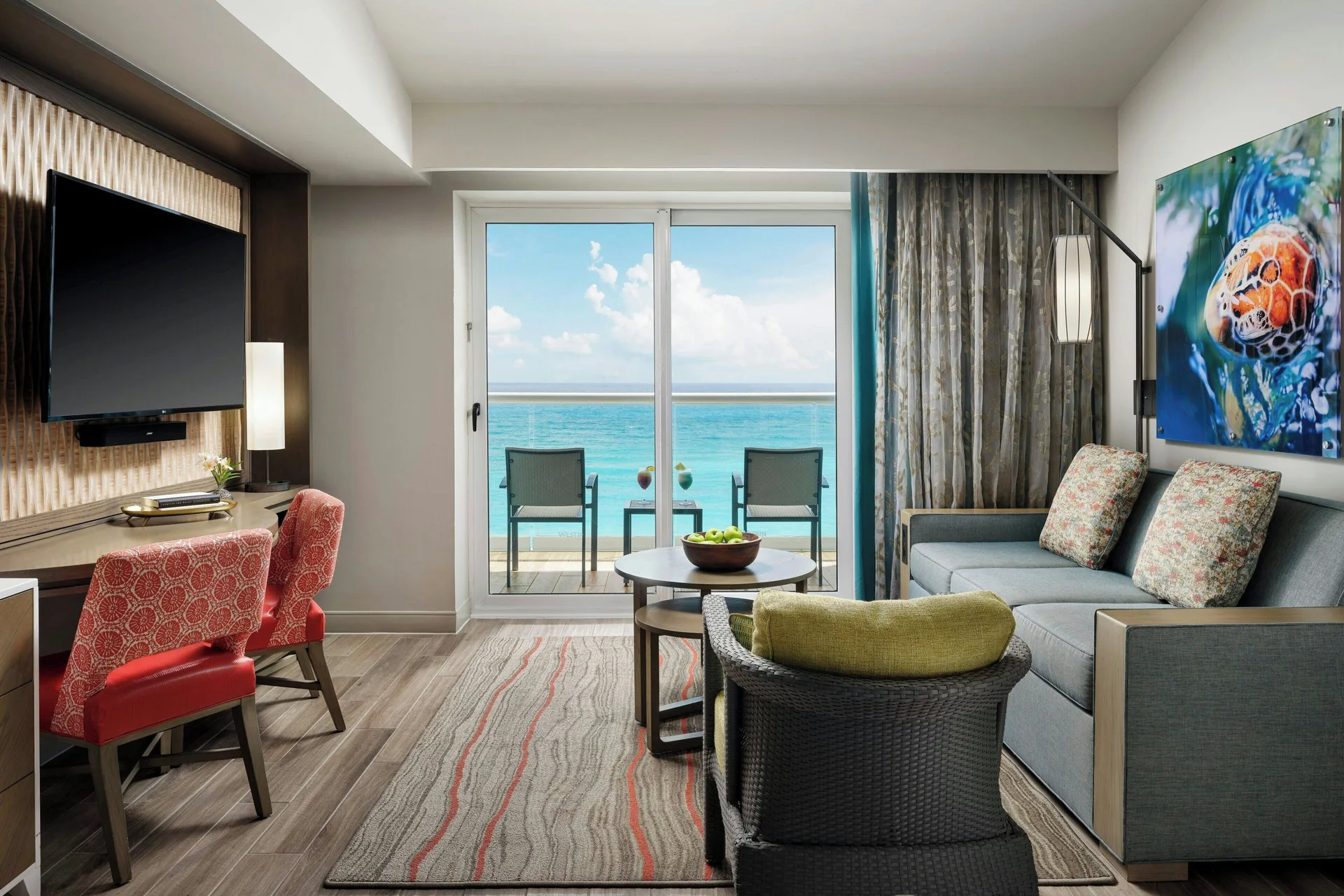 Studio sofa bed, desk, TV, and ocean-view balcony at The Westin Resort & Spa, Cancun.