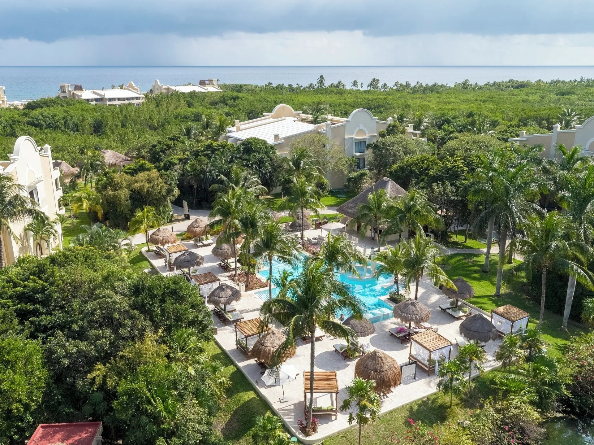 An aerial view shows palms, pools, and resort buildings at TRS Turquesa Hotel.