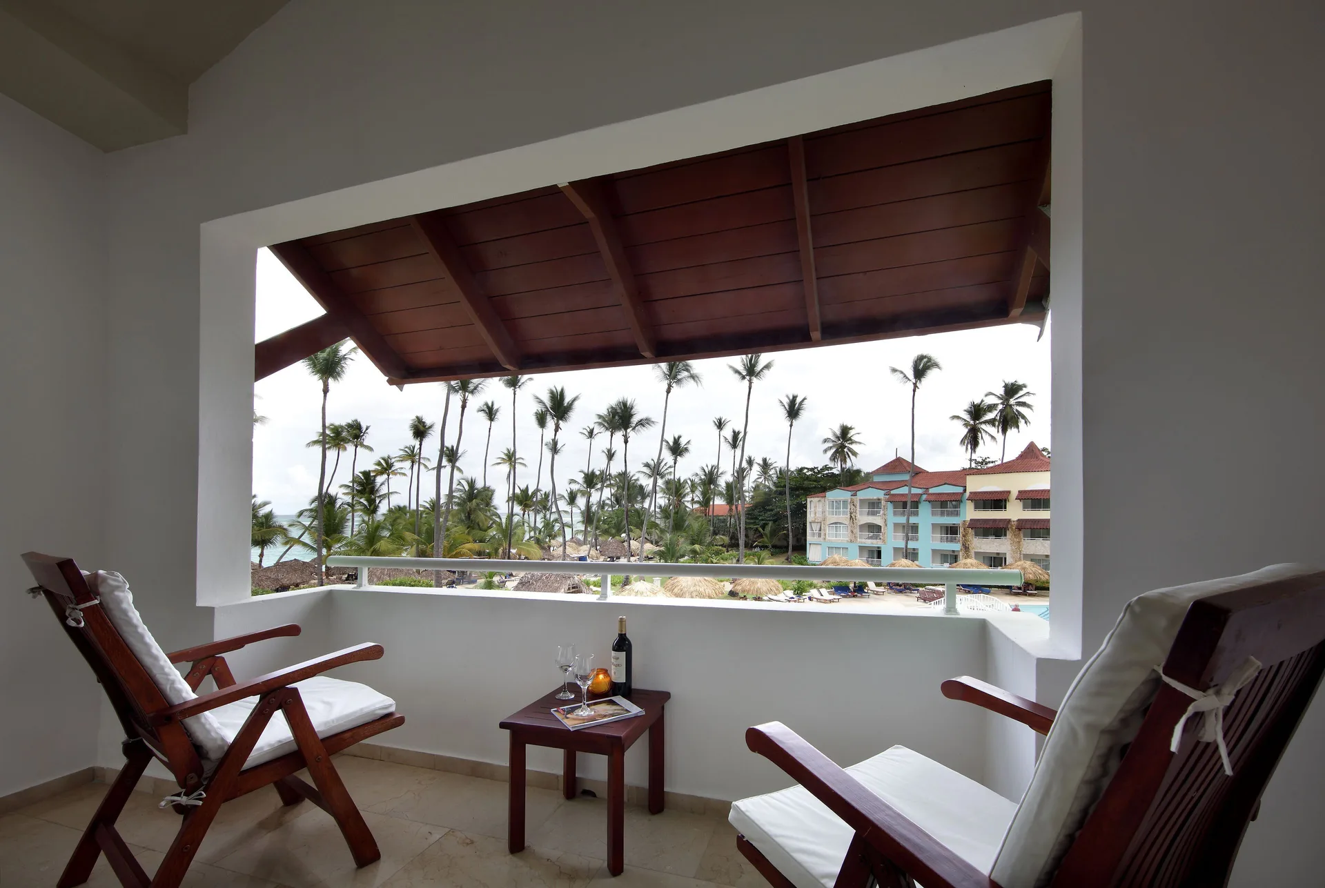 A covered balcony with two chairs overlooks palms and the sea at TRS Turquesa Hotel.
