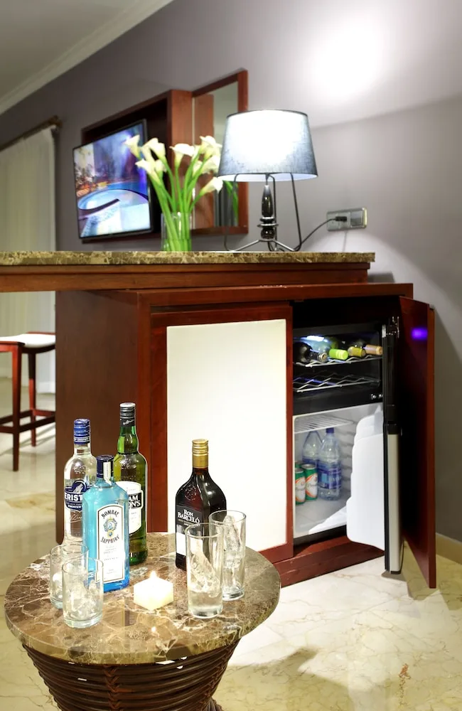 In-room minibar with bottles, glasses, mini fridge, flowers, and TV at TRS Turquesa Hotel.