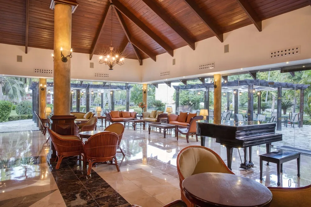 Lobby lounge with piano, wicker seating, and garden views at TRS Turquesa Hotel.
