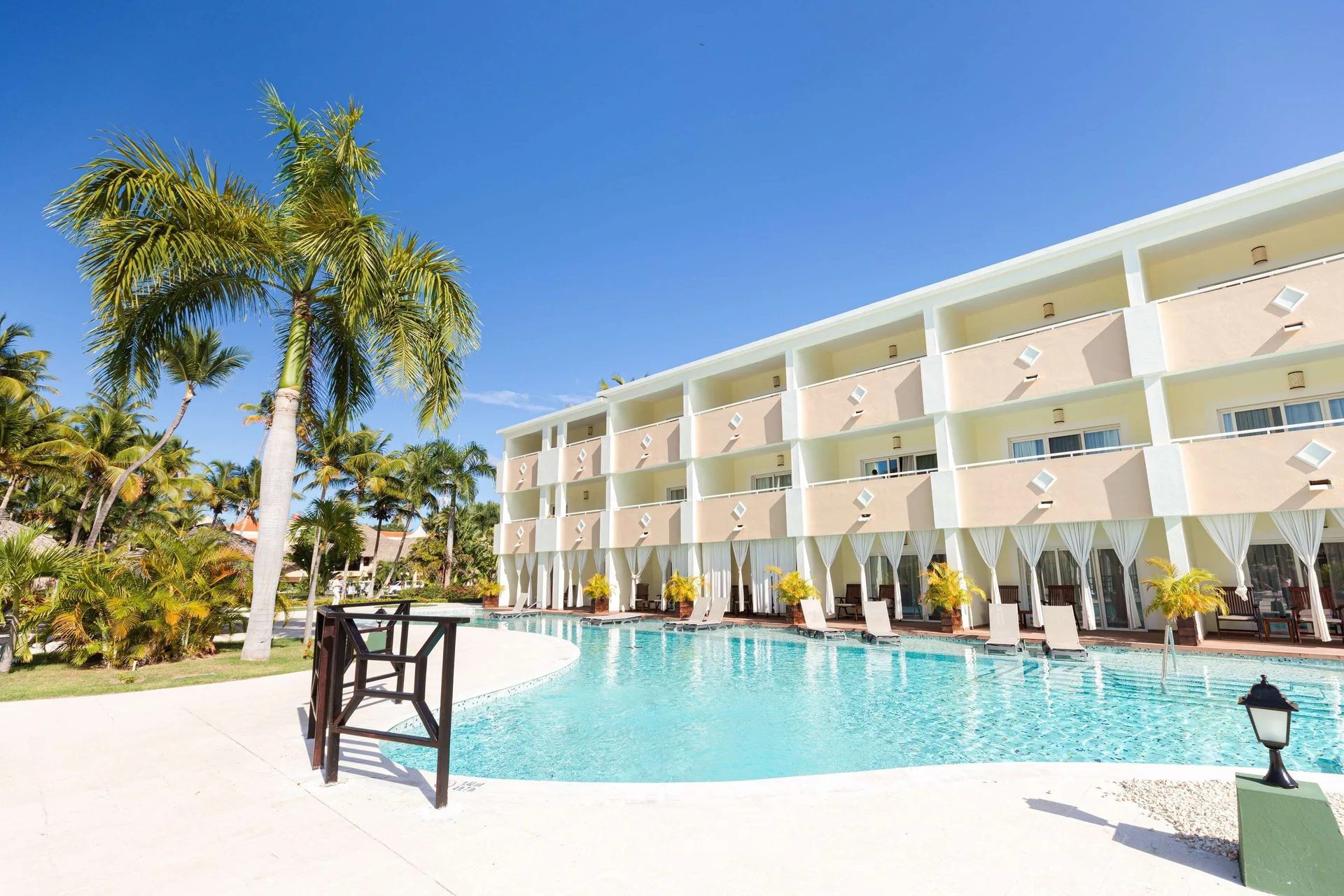 A palm-lined pool curves along a guest building at TRS Turquesa Hotel.