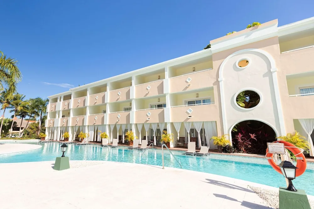 Swim-up pool beside a pale pink guest building at TRS Turquesa Hotel.