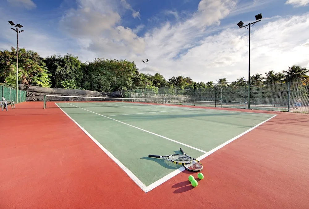 Tennis court with rackets and balls on the surface at TRS Turquesa Hotel.