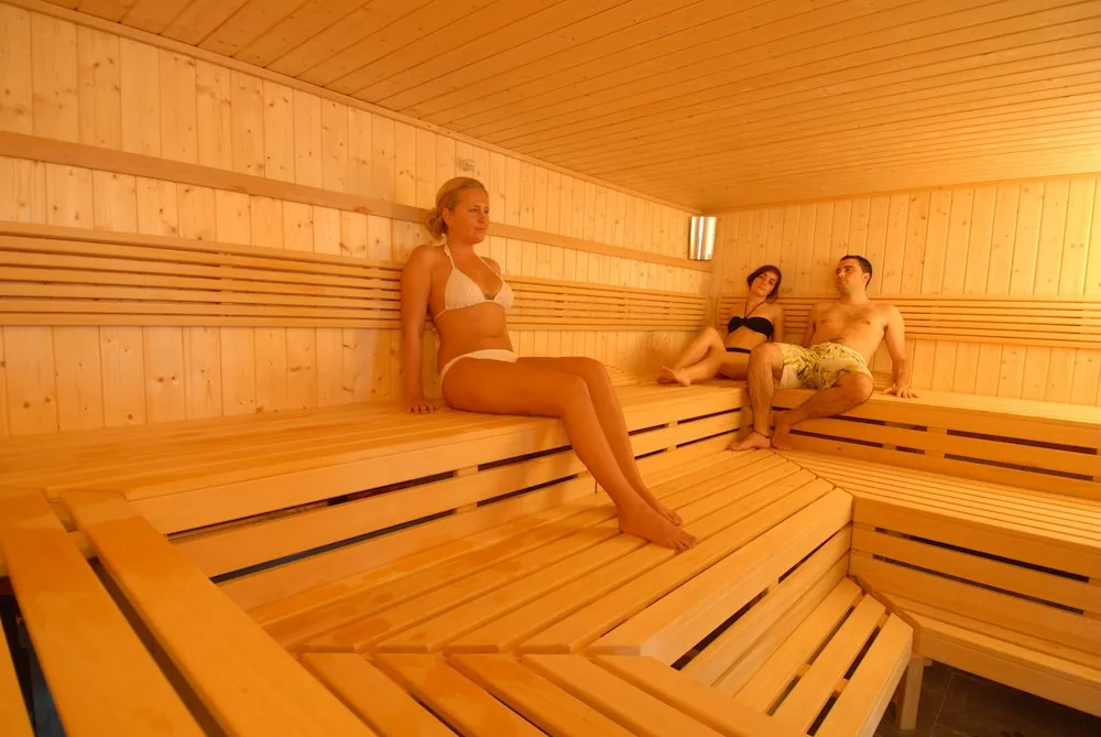 Guests relax on tiered wooden benches inside the sauna at TRS Turquesa Hotel.
