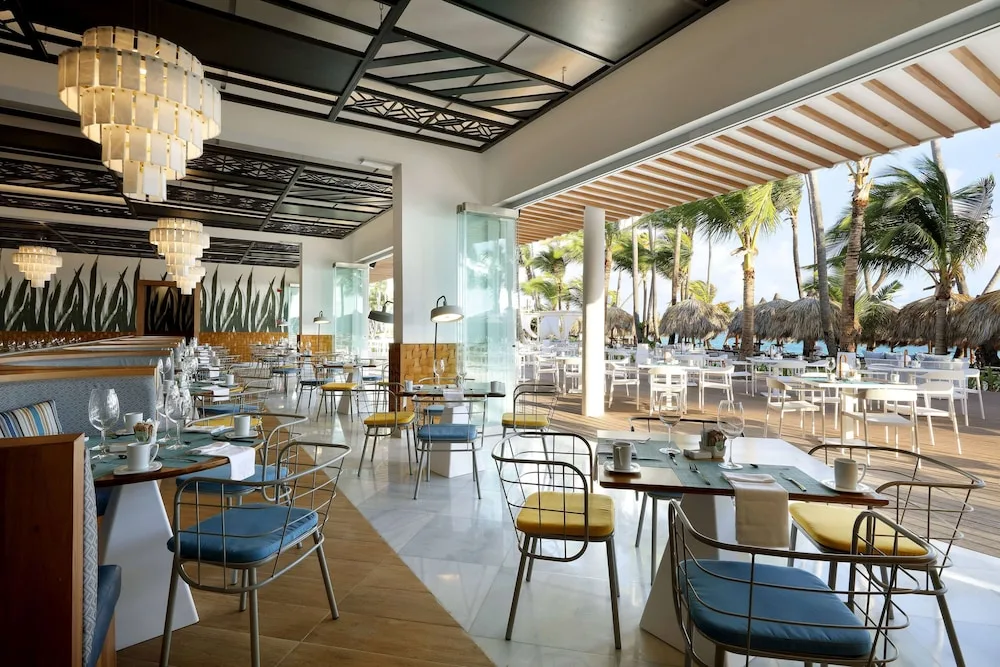 Open-air beachfront dining terrace with palm views at TRS Turquesa Hotel.