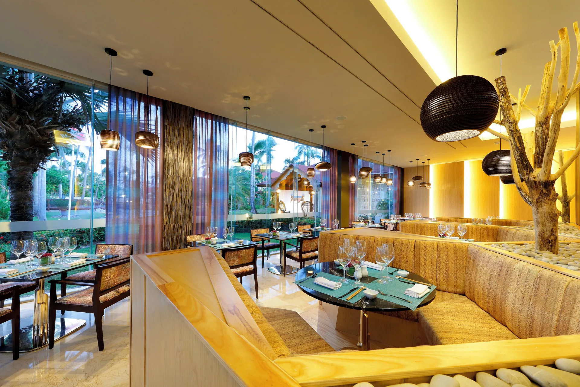Warm restaurant dining room with round tables and woven pendant lights at TRS Turquesa Hotel.