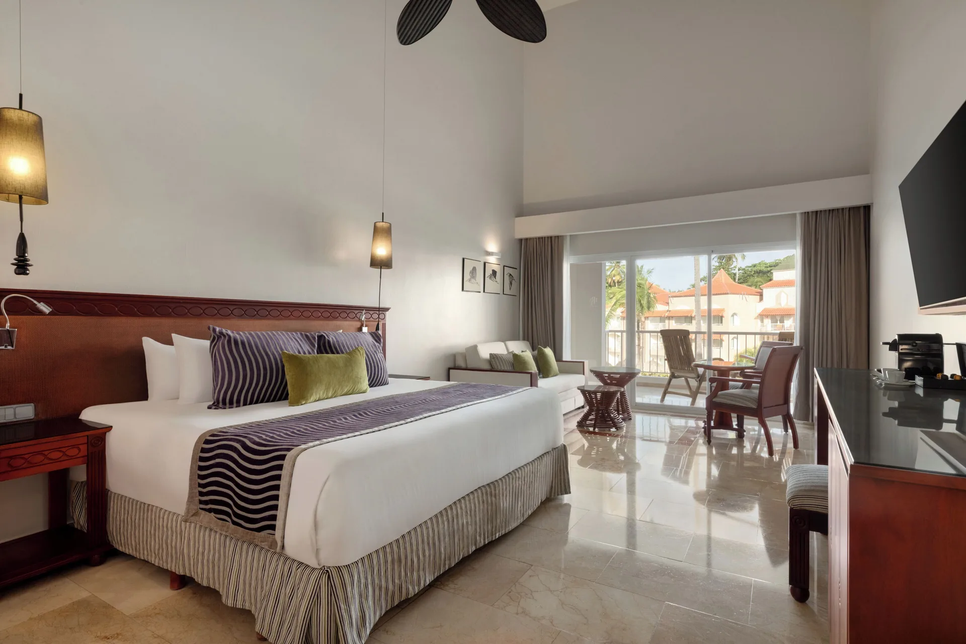 Junior Suite Poolside king bed with sofa, desk, balcony, and high ceiling at TRS Turquesa Hotel.