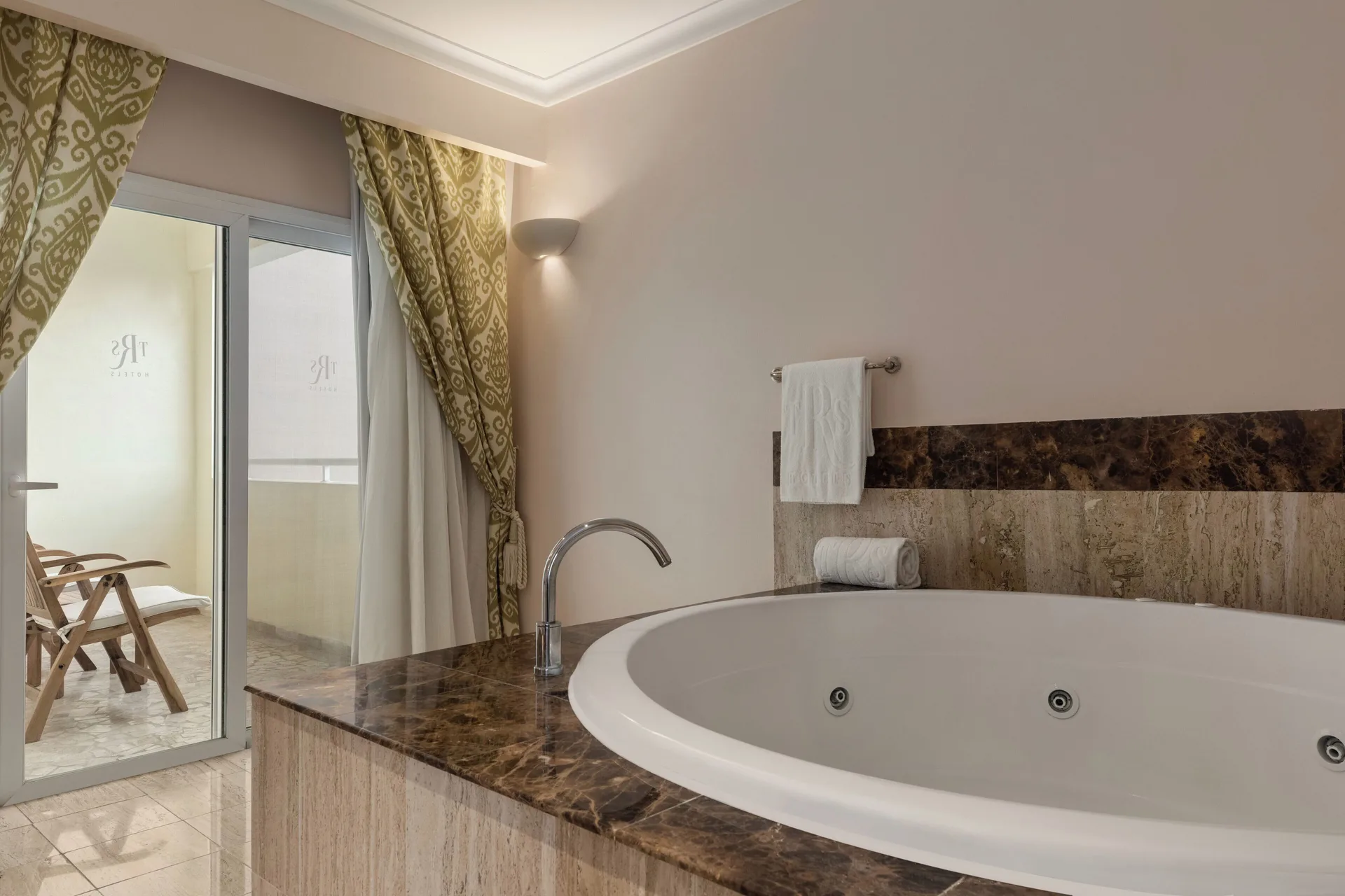 Romance Suite Poolside jetted tub beside balcony doors at TRS Turquesa Hotel.