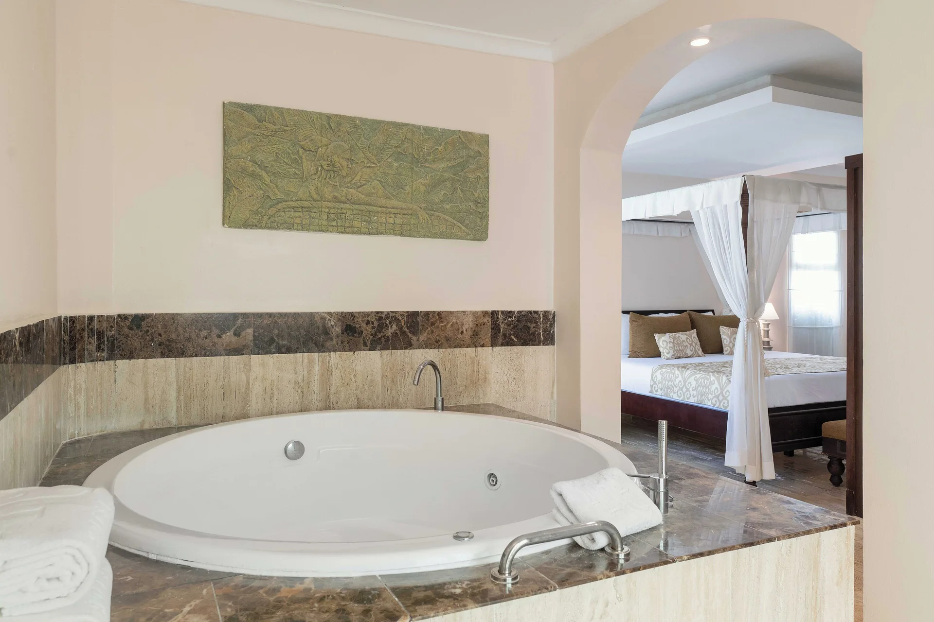 Romance Suite Swim Up round tub with canopy bed beyond at TRS Turquesa Hotel.