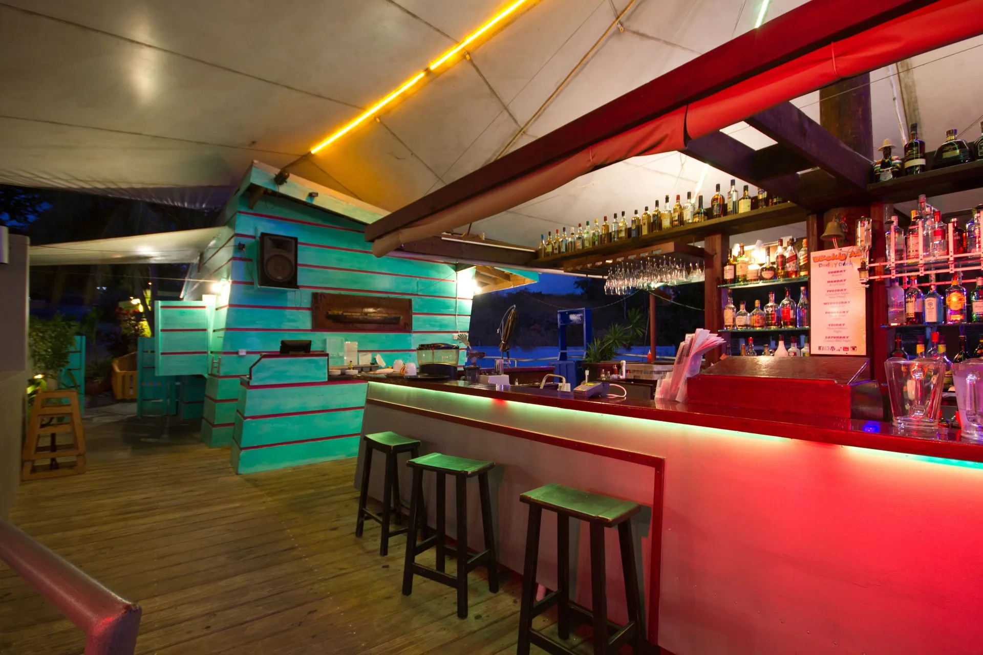 Open-air bar with colorful lighting and stools at True Blue Bay Resort.