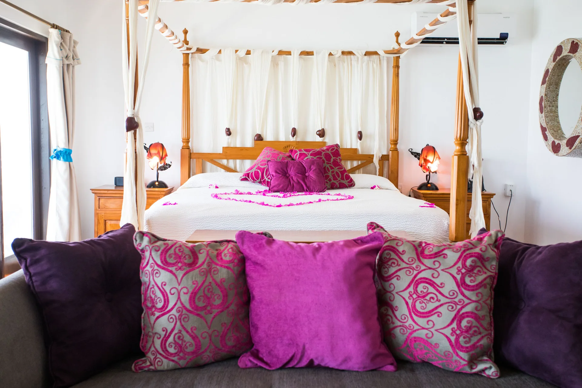 Tower Suite four-poster bed with bright pillows at True Blue Bay Resort.
