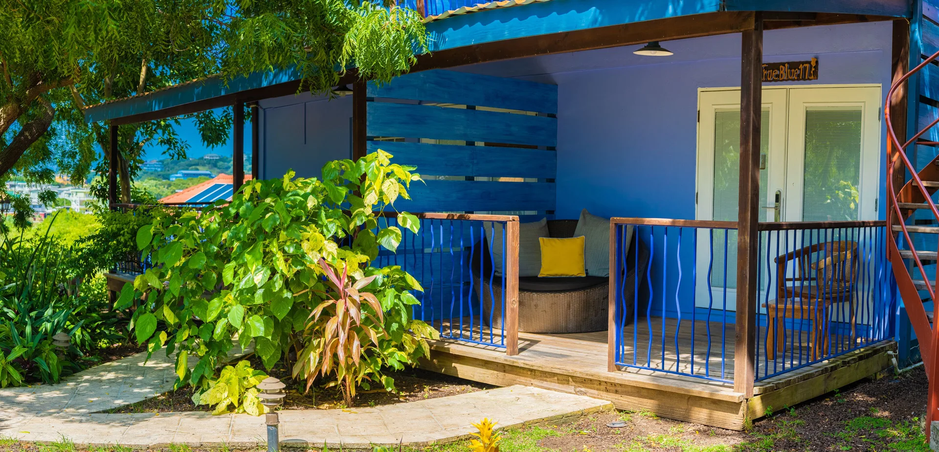 True Blue Bay Resort exterior patio at True Blue Bay Resort with blue railings and garden plants.