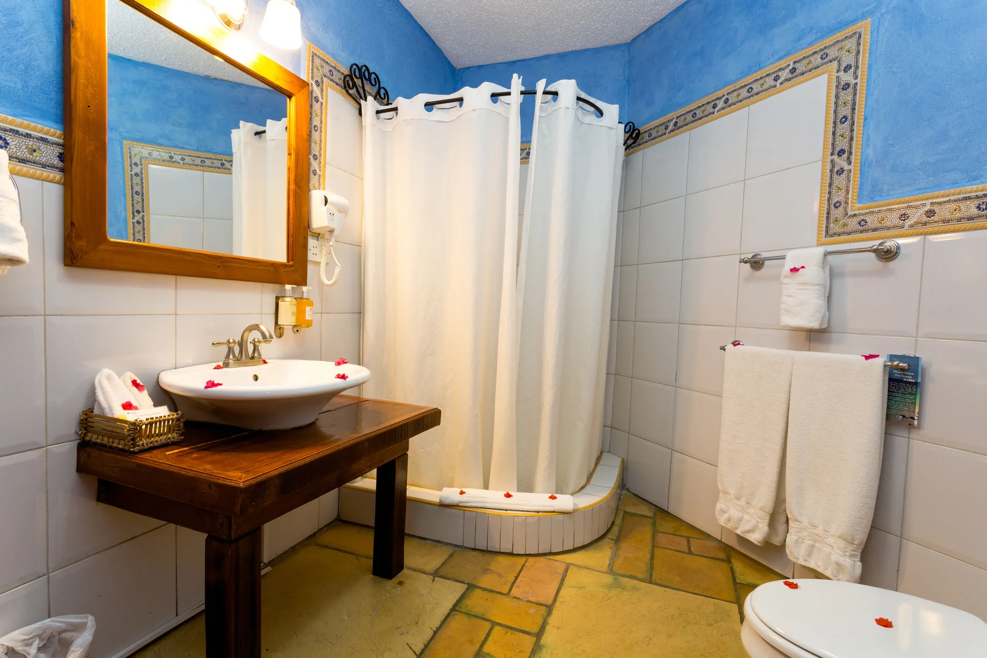 True Blue Bay Resort bathroom at True Blue Bay Resort with blue walls, sink, towels, and curtained shower.