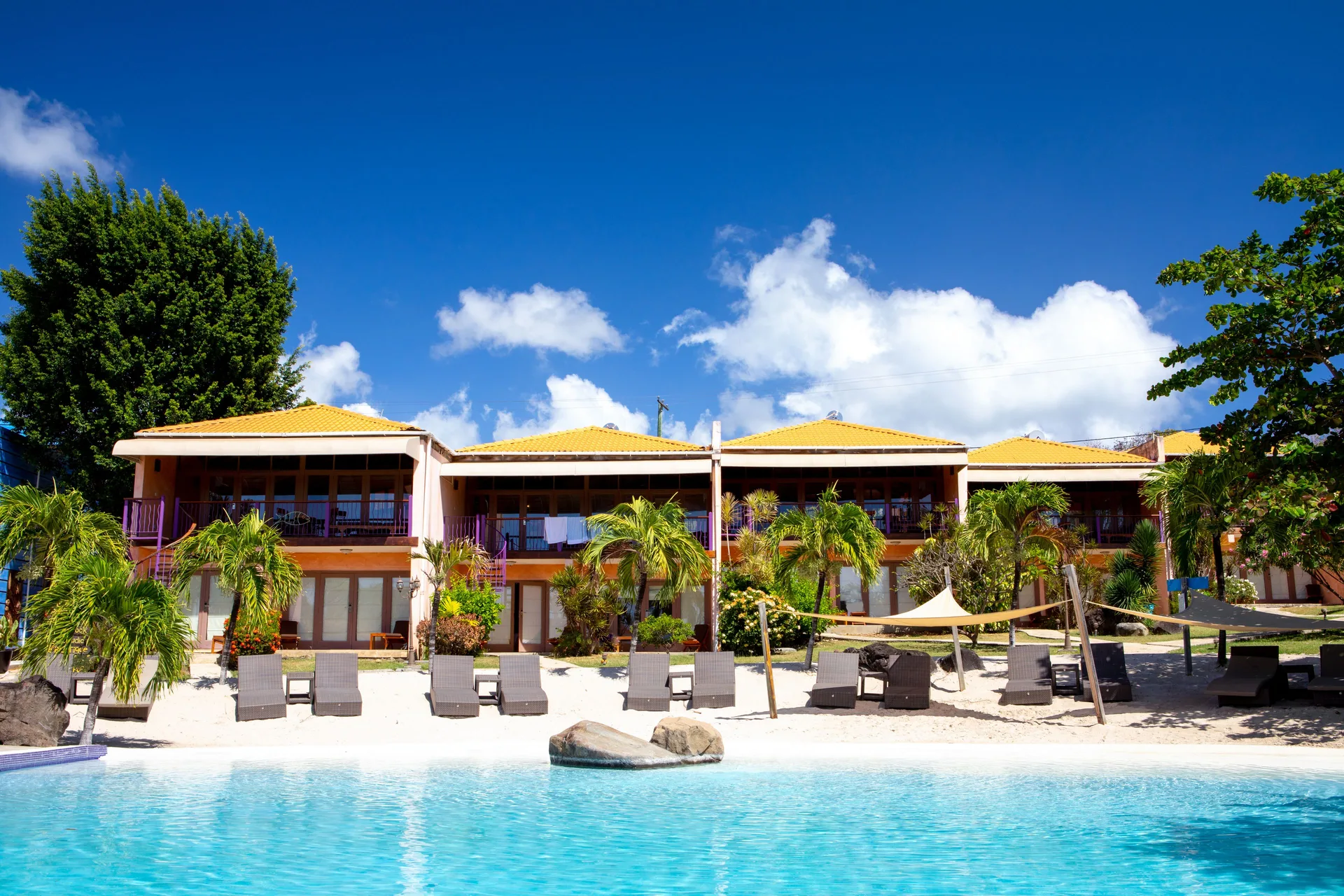 True Blue Bay Resort buildings beside the pool and sandy lounge area at True Blue Bay Resort.