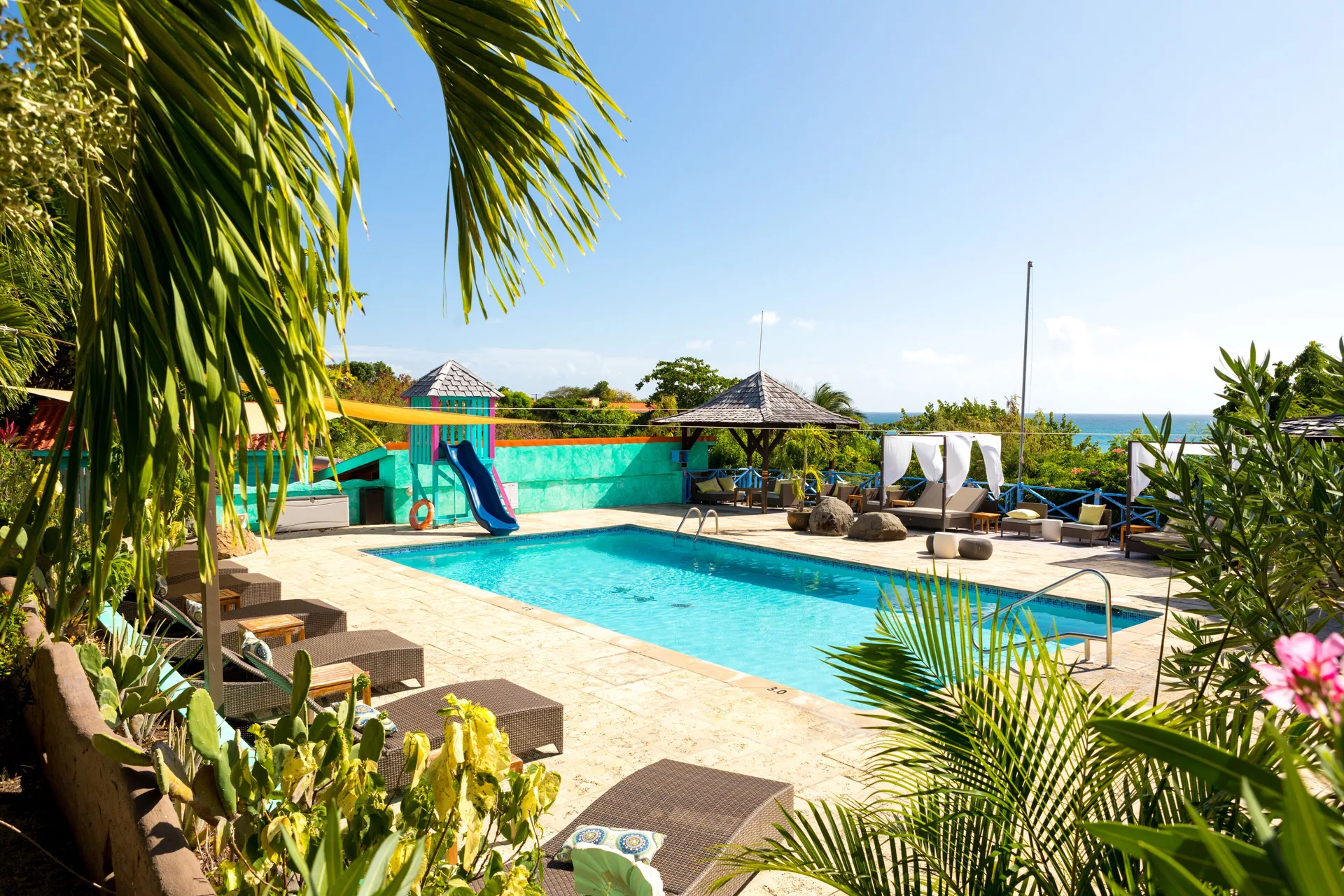 Pool with loungers and tropical landscaping at True Blue Bay Resort.