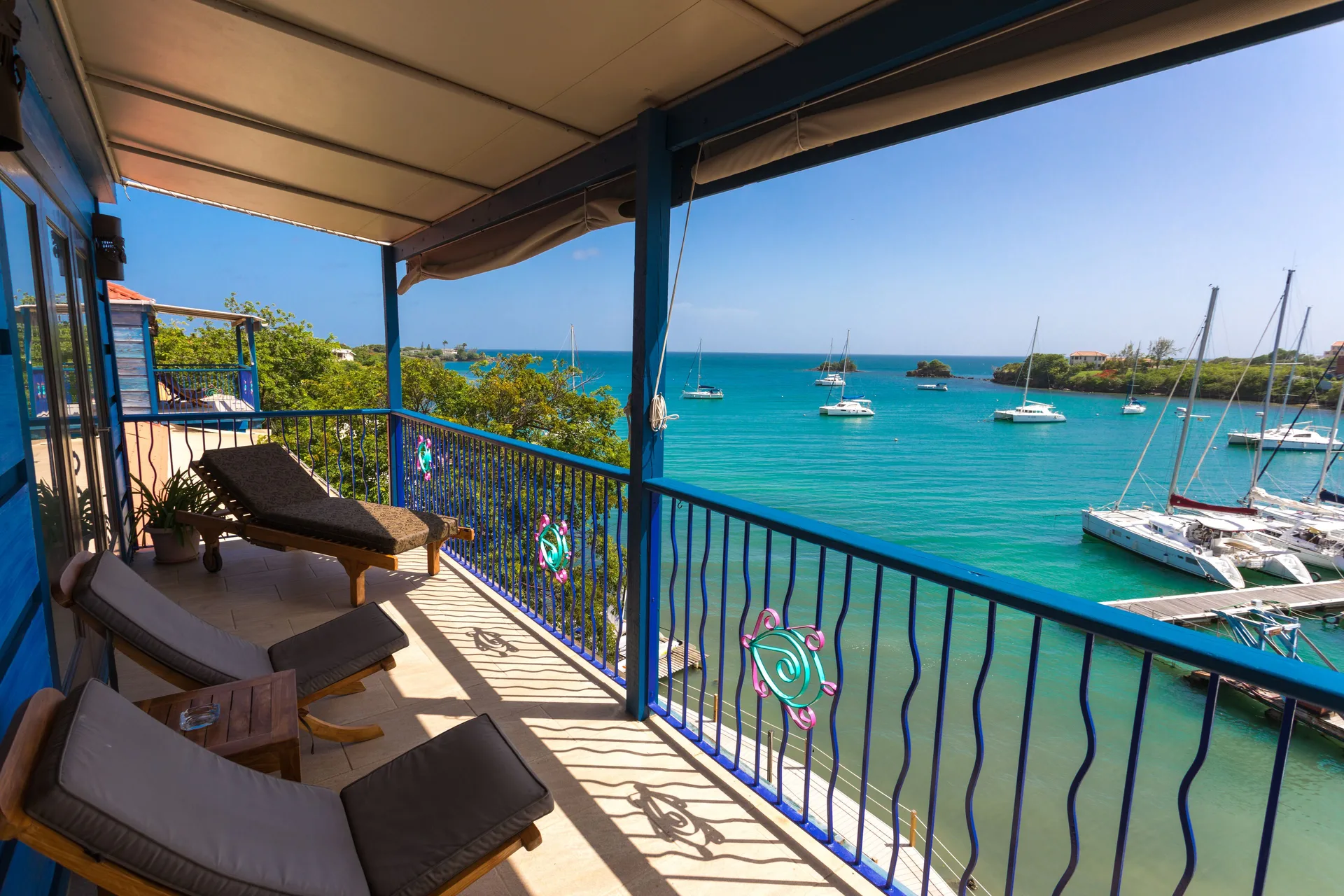 Waterfront Suite balcony with loungers and bay view at True Blue Bay Resort.
