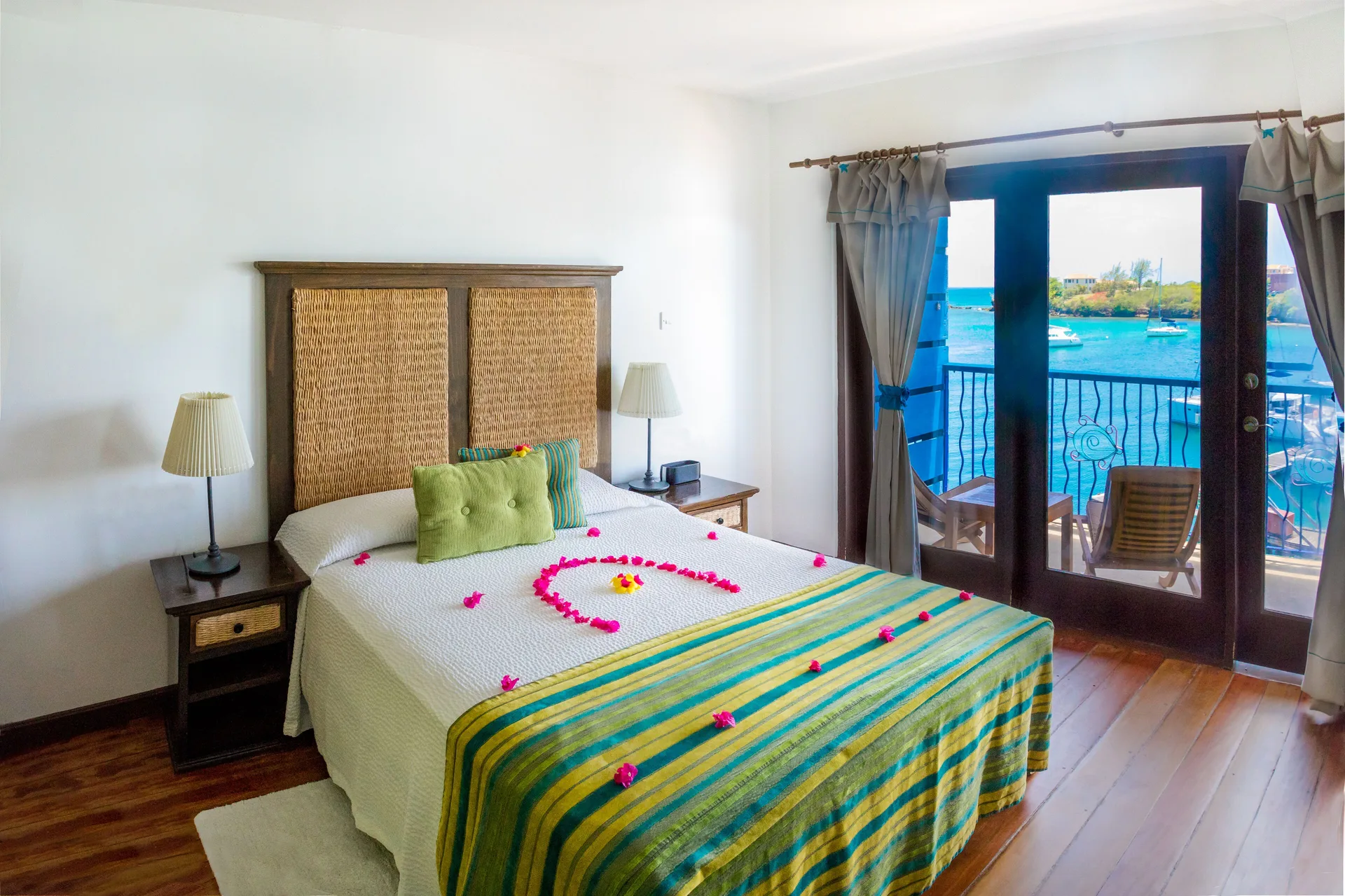 Waterfront Suite queen bed and balcony doors at True Blue Bay Resort.