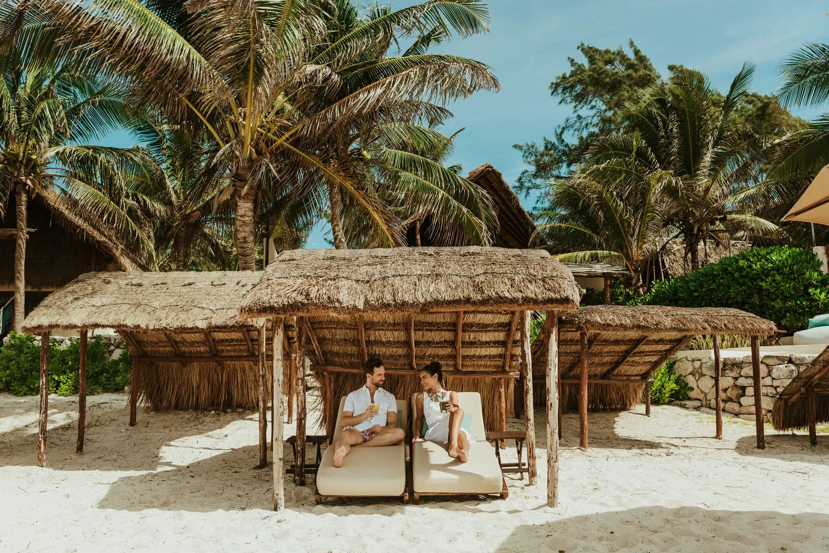 Beach loungers under thatched shade structures at Viceroy Riviera Maya.