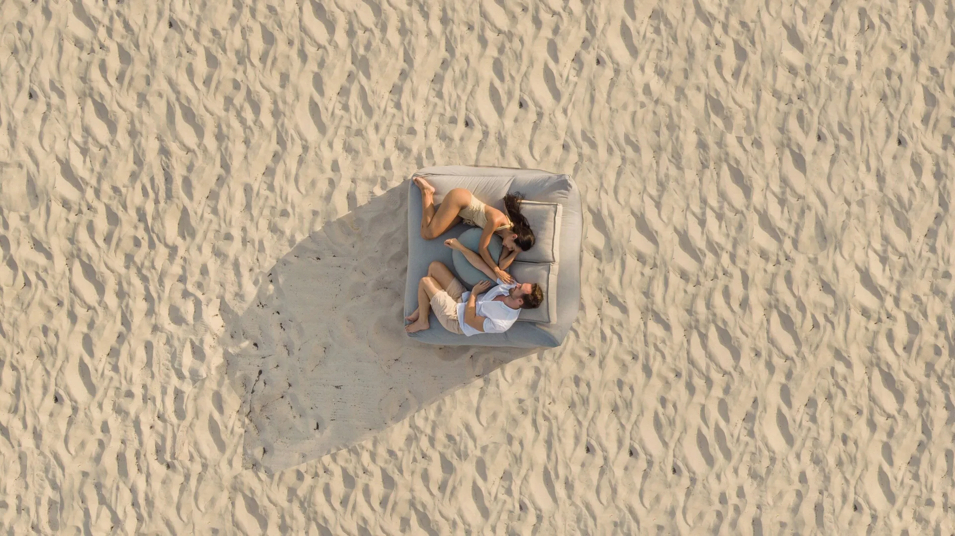 Overhead view of a couple lounging on a cushioned beach bed at Viceroy Riviera Maya.