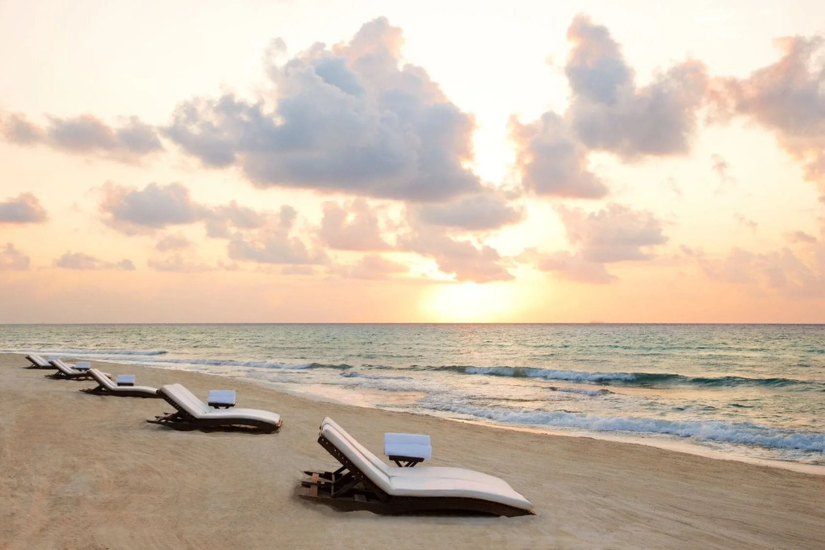 Beach loungers face the sunrise over the Caribbean at Viceroy Riviera Maya.