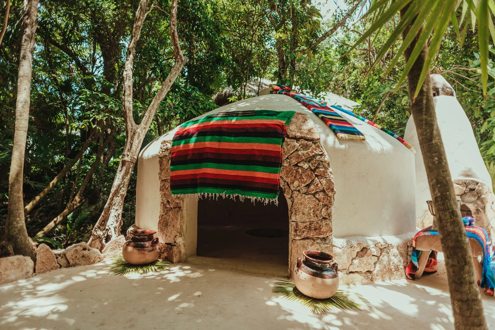 Domed temazcal structure draped with colorful textiles at Viceroy Riviera Maya.