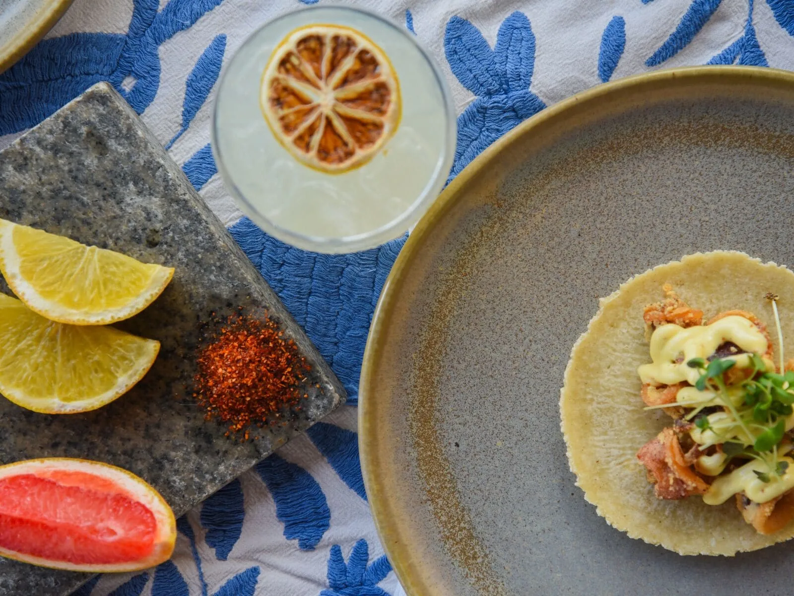A taco, citrus wedges, chile powder, and a cocktail are arranged at Viceroy Riviera Maya.