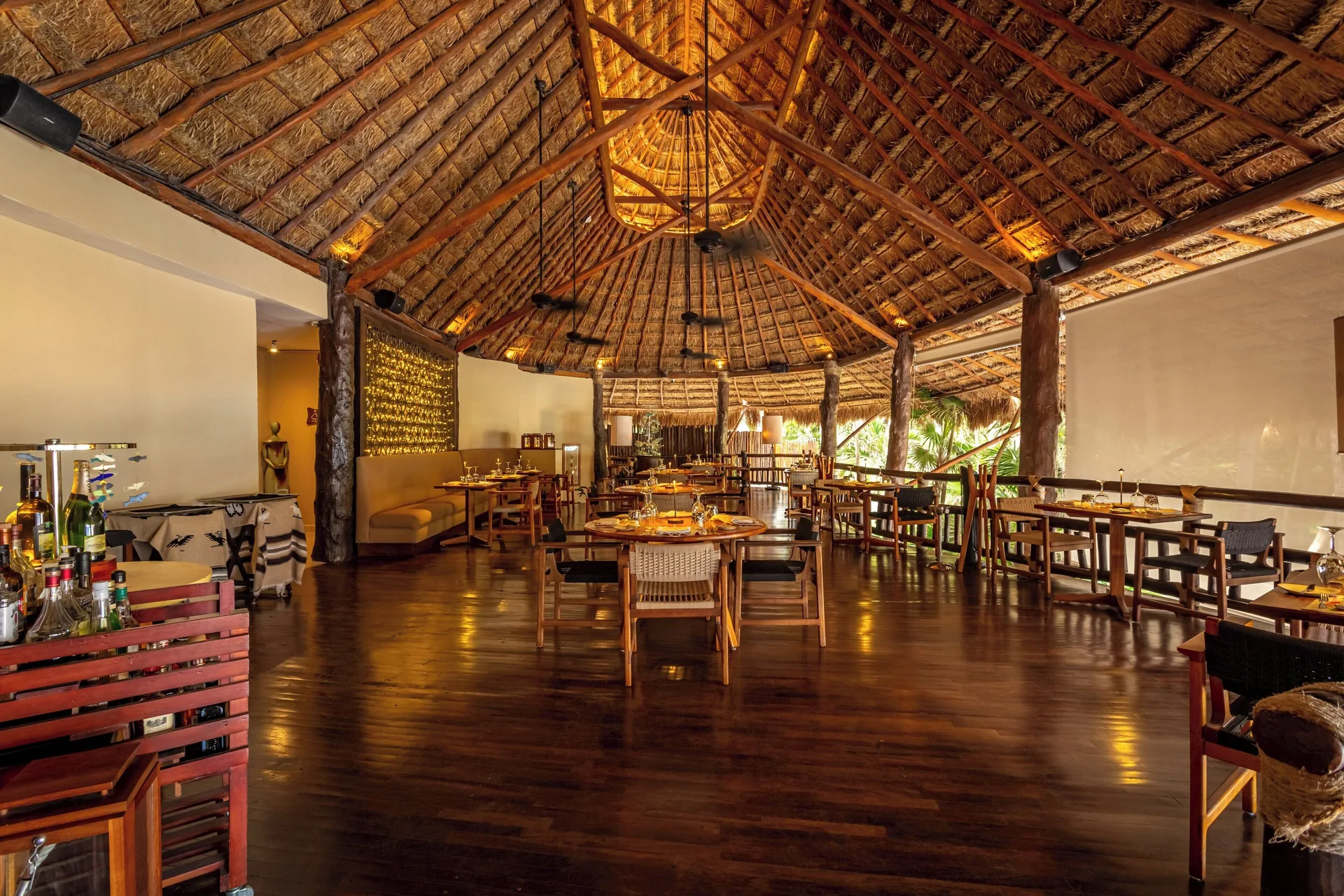 Thatched-roof restaurant dining room with set tables at Viceroy Riviera Maya.